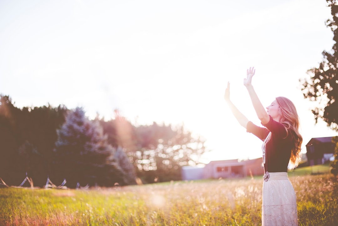 A Girl Standing In A Field With Her Hands Up