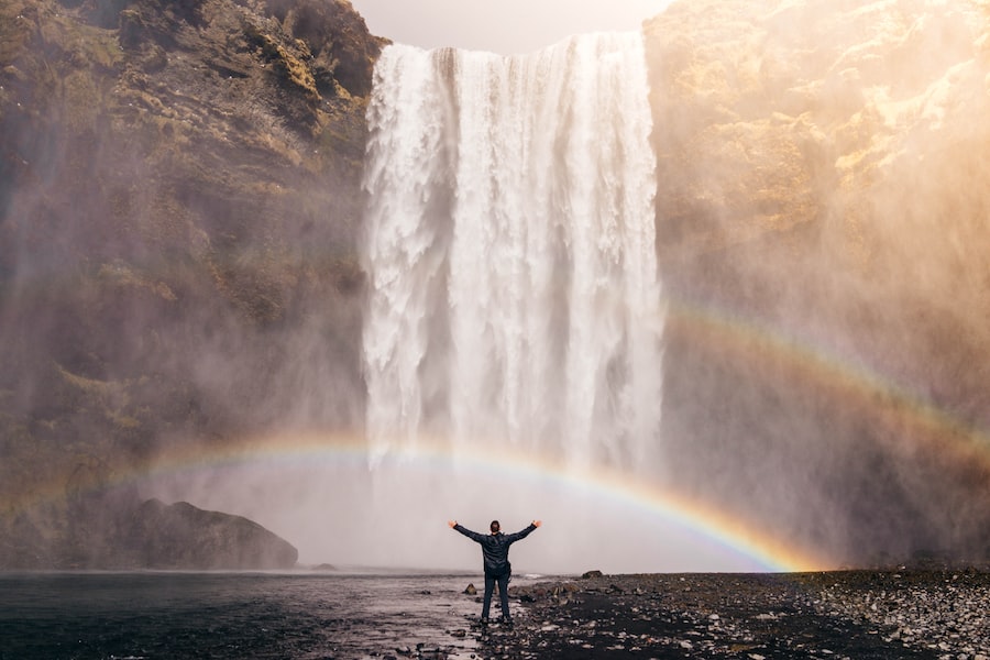 A Person Standing In Front Of A Waterfall